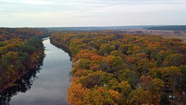 Autumn aerial speedup forward flight above river with vibrant forest on riverbanks. Cossack mountain, Koropove village on Siverskyi Donets River in Ukraine