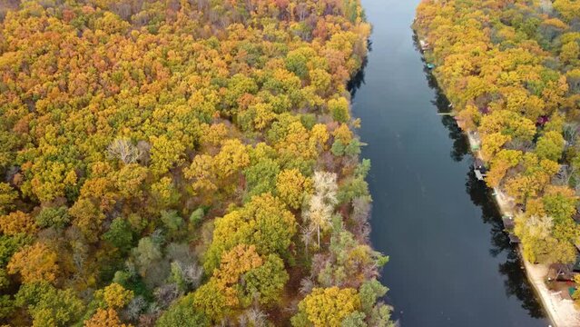 Autumn aerial tilt down view on river with wooded colorful forest riverbanks. Siverskyi Donets River in Ukraine