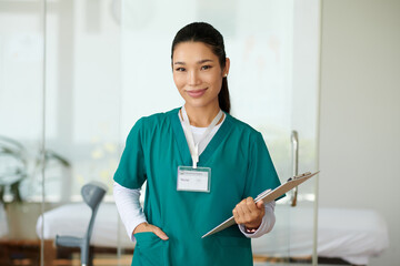 Portrait of young smiling nurse of rehabilitation center holding clipboard