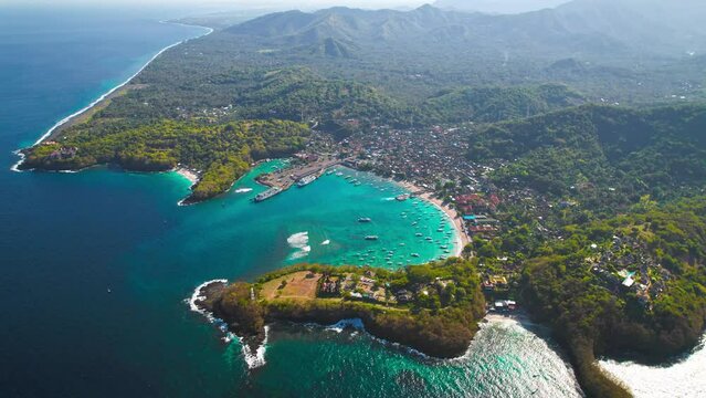 Bali Island blue lagoon beach aerial around Padangbai port marina. Drone panoramic parallax at beautiful ocean sea travel holiday resort.