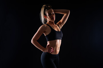 Beautiful young woman dressed in sports uniform, posing in studio on a yellow red dark background.