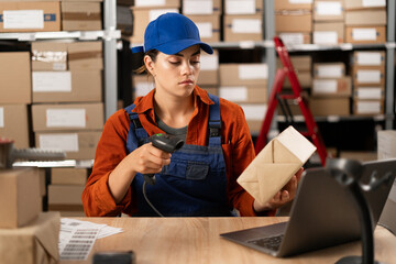 Female seller worker using scanner scanning parcel barcode tag, post shipping box, orders in dropshipping delivery service. Warehouse concept - obrazy, fototapety, plakaty