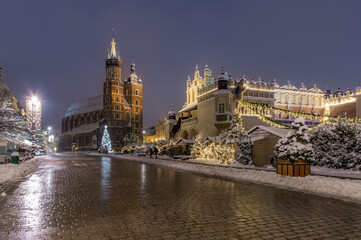 Krakow, Poland, snowy Main Market square, St Mary's church and Cloth Hall in the winter season, during Christmas fairs decorated with Christmas tree - 688192994