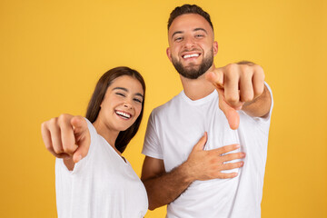 Smiling confident young european man and lady in white t-shirts point finger at camera