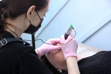 Permanent lip makeup. The cosmetologist makes the procedure of permanent makeup