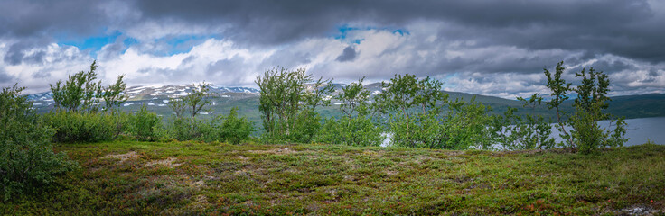 Scenic wide panorama on high altitude Norwegian Mountains range terrain with mountains, clouds and lake at horizon line. Hiking destination high in Norwegian mountains. Norway, Krutvatnet.