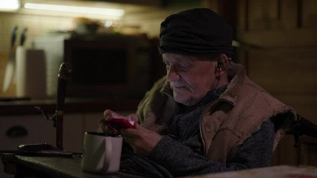 Senior man sitting in wheelchair scrolling on social media on smartphone