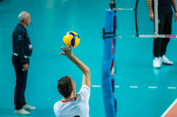 Volleyball player sreves ball, referee in the background. - obrazy, fototapety, plakaty