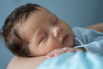 Mom holds a newborn boy, the baby sleeps sweetly. Mother's hands and baby close-up. Infant health...