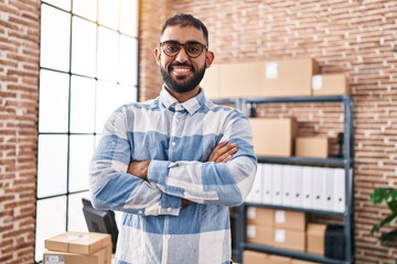 Young hispanic man ecommerce business worker standing with arms crossed gesture at office
