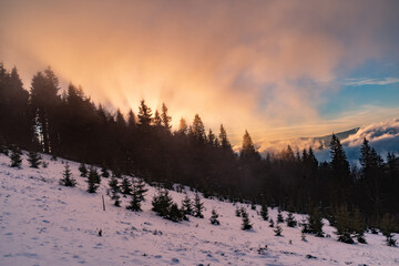 Sunset in the winter mountains. Rays of the sun from behind the winter mountains. Beautiful winter landscape.
