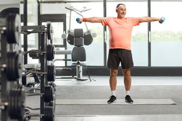 Mature man exercising with small weights at a gym