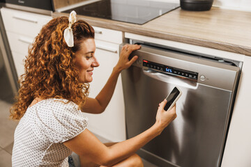 Woman Using Mobile App To Control Dishwasher