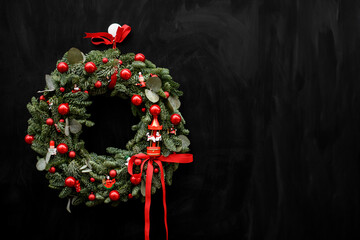 Christmas wreath decorated with red ribbons, red balls of different colors and figurines of...
