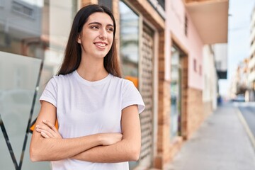 Young beautiful hispanic woman standing with arms crossed gesture at street