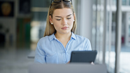 Young blonde woman business worker using laptop and touchpad at office