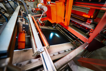 A wide belt of raw rubber compound moves along a roller conveyor. Plant for the production of car...