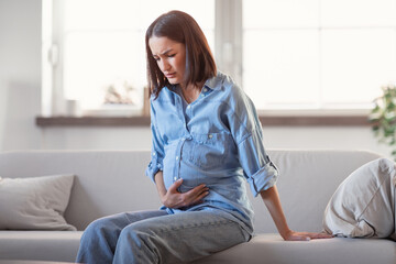 Unhappy Pregnant Lady Suffering From Abdominal Pain Touching Belly Indoors