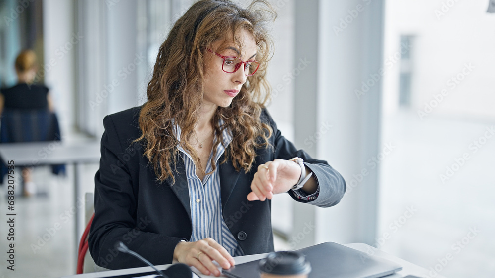 Poster Young woman business worker looking watch at the office