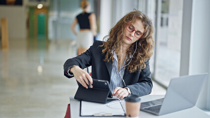 Young woman business worker using touchpad and earphones working at the office