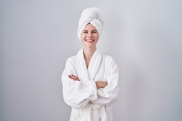 Blonde caucasian woman wearing bathrobe happy face smiling with crossed arms looking at the camera. positive person.