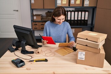 Young blonde woman ecommerce business worker using touchpad holding package at office