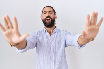 Naklejka premium Hispanic man with beard wearing casual shirt doing stop gesture with hands palms, angry and frustration expression