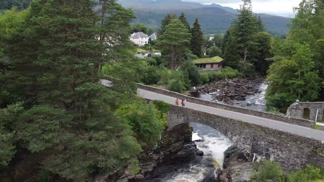 Aerial view of couple taking a selfie on bridge over waterfall in Killin, United Kingdom. 