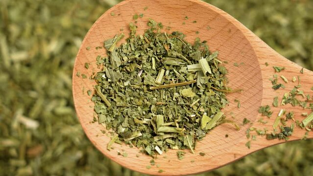 Dried Passiflora green herbs in wooden spoon close up. Passion flower herbal leaves for sleeping