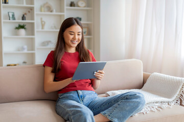 Fototapeta premium Portrait Of Beautiful Smiling Asian Woman Resting On Couch With Digital Tablet