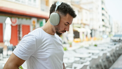 Young arab man listening to music at coffee shop terrace