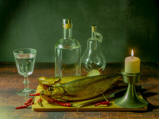 Still life in antique style with fish and alcohol on a wooden table. - 688211905