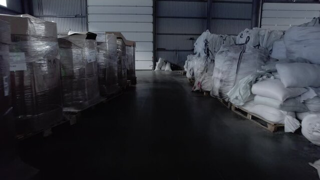 Storeroom shelters broad containers filled with raw materials. Sacks filled with secondary raw materials positioned for chemical fertilizer production
