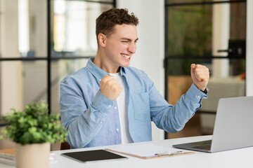 Naklejka premium Happy excited millennial caucasian man manager rise fists, celebrate win