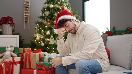 Obraz na płótnie Canvas Young hispanic man celebrating christmas stressed at home