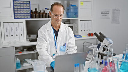 Fototapeta na wymiar Middle age man scientist using laptop at laboratory