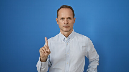 Handsome mature man, in cool casual fashion, seriously gesturing 'no' with his finger, standing...