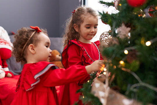 Adorable girls smiling confident decorating christmas tree at home