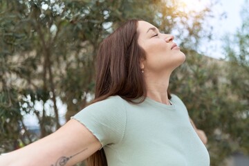 Naklejka premium Young beautiful woman breathing with closed eyes at park