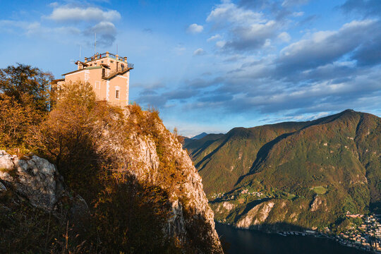 Wide-angle sunset view from the summit of Monte San Salvatore overlooking Lake Lugano Breathtaking panorama of the city, Melide causeway and the Swiss Alps in Ticino, Switzerland - November 2023