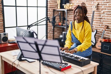 African american woman musician smiling confident playing piano at music studio