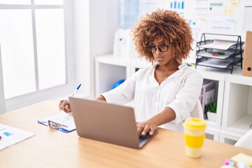 African american woman business worker using laptop writing on document at office