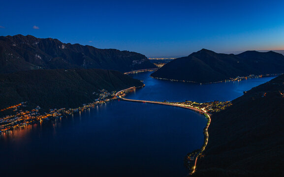Wide-angle sunset view from the summit of Monte San Salvatore overlooking Lake Lugano Breathtaking panorama of the city, Melide causeway and the Swiss Alps in Ticino, Switzerland - November 2023