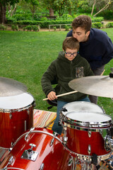 Fototapeta na wymiar Tender moment: Older brother giving a gentle kiss on his younger brother's forehead while teaching him to play the drums. Down syndrome.