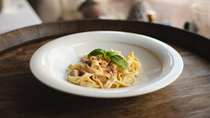 Italian food. Pasta with meat and creamy sauce in a deep white plate.