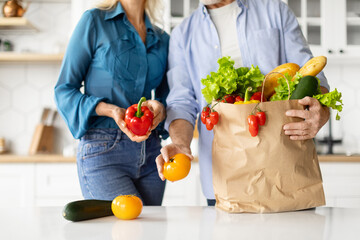 Unrecognizable Senior Couple Taking Out Fresh Vegetables Of Paper Groceries Bag