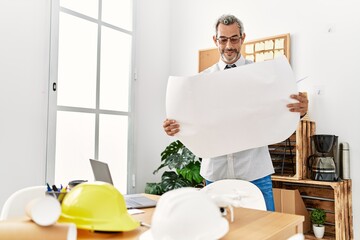 Middle age grey-haired man architect looking house plans at office