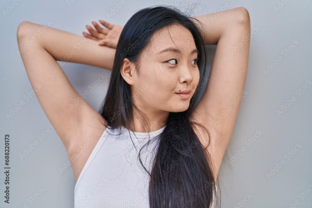 Sticker Young chinese woman smiling confident relaxed with hands on head over isolated white background