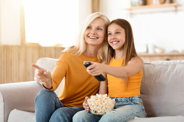 Obraz premium Happy granddaughter and grandmother watching movie at home