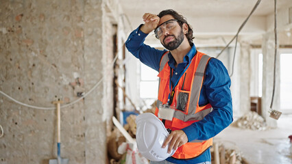 Young hispanic man architect sweating at construction site